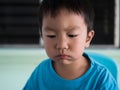 Asian child boy in blue t shirt eating and chewing food in mouth at home