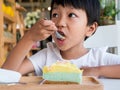 Asian child boy eat sweet cake in cafe with happy delicious face.