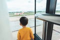 Asian child boy looking airplane through window. Back view