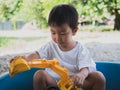 Asian child boy playing backhoe car toy and sand in sandbox. Royalty Free Stock Photo