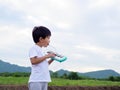 Asian child boy playing, blowing melodeon musical instrument. Kid make music song with happy relaxing face in nature field Royalty Free Stock Photo