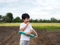 Asian child boy playing, blowing melodeon musical instrument. Kid make music song with happy relaxing face in nature field Royalty Free Stock Photo