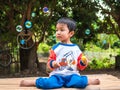 Asian child boy playing bubbles outdoor with happy smiling face with natural rural green background. Royalty Free Stock Photo