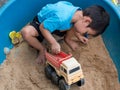 Asian child boy playing car toy in sandbox outdoor with smiling face. Royalty Free Stock Photo