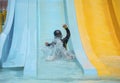 Asian child boy playing happiness a slider down to the swimming pool, kid learning activity concept