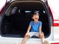 Asian child boy smile and laugh with happy face in rear of white car.