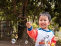 Asian child boy smiling with happy face while playing bubbles outdoor with natural rural background. Royalty Free Stock Photo