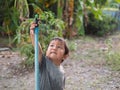 Asian child boy turning sprinkler with serious face in garden at home. Royalty Free Stock Photo