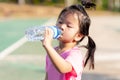 Asian child are drinking some water from plastic bottles. Cute girl thirsty. Hot summer or spring. Children sweats on the face.