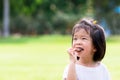 Asian child eating chocolate. Cute girl biting delicious wafers. On green laws nature background. Summer or spring time.