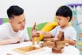 Asian child and father playing with wooden blocks in the room at home. A kind of educational toys for preschool and kindergarten Royalty Free Stock Photo