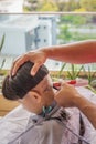 Asian child getting haircut at home from the father. Young boy save his head using electric razor Royalty Free Stock Photo