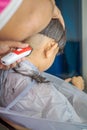 Asian child getting haircut at home from the father. Young boy save his head using electric razor Royalty Free Stock Photo