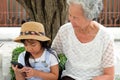 Asian child girl is addictive play mobile phone addicted to the game, have an elderly grandmother sit with caring concern