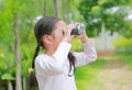 Asian child girl with binoculars in nature fields. Explore and adventure concept