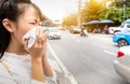 Asian child girl blowing nose in paper handkerchief,female person sneeze in a tissue in city street,toxic fumes from car,bad smell Royalty Free Stock Photo