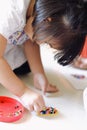 Asian child girl is connecting a toy onto a plastic sheet