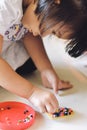 Asian child girl is connecting a toy onto a plastic sheet