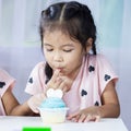 Asian child girl eating delicious blue cupcake