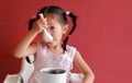 Asian child girl eating pork bone soup on high chair against red wall background at chinese restaurant Royalty Free Stock Photo