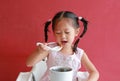 Asian child girl eating pork bone soup on high chair against red wall background at chinese restaurant Royalty Free Stock Photo