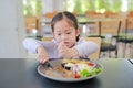 Asian child girl eating Pork steak and vegetable salad on the table with holding knife and fork. Children having breakfast Royalty Free Stock Photo