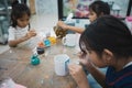 Asian child girl and friends are concentrating to paint on ceramic glass with oil color together with fun. Kids arts and crafts