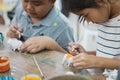 Asian child girl and friends are concentrating to paint on on small ceramic elephant with oil color together with fun. Royalty Free Stock Photo