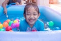 Asian Child Girl Having Fun In Garden Paddling Pool with father fill wather in background