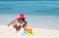 Asian child girl having fun to play with sand on beach in summer vacation Royalty Free Stock Photo
