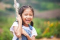 Asian child girl having fun to play on wooden swings in playground with beautiful nature