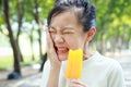 Asian child girl having hypersensitive teeth eating ice-pop,feel painful,female teenage have sensitive teeth with ice-lolly,sad