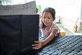 Asian child girl helping parents to carry a cardboard box with stuffs moving into the car to relocation on moving day. Royalty Free Stock Photo