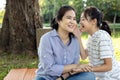 Asian child girl hold hand near mouth telling funny or gossips on ears to female people,daughter always gossips about others or