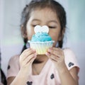 Asian child girl holding delicious blue cupcake