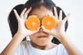 Asian child girl holding fresh oranges covering her eyes. Kid having fun to play with fresh fruit Royalty Free Stock Photo