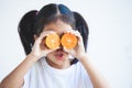 Asian child girl holding fresh oranges covering her eyes. Kid having fun to play with fresh fruit Royalty Free Stock Photo