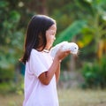 Asian child girl holding and hugging her adorable bunny fluffy with tenderness and love. Kid take care and play with pet