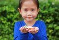 Asian child girl holding some thai sugar and fruit toffee with colorful paper wrapped in her hands. Focus at candy in her hands Royalty Free Stock Photo