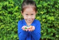 Asian child girl holding some thai sugar and fruit toffee with colorful paper wrapped in her hands. Focus at candy in her hands Royalty Free Stock Photo