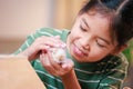 Asian child girl holding tiny bunny in hand with tenderness and love. Kid take care a pet and decorate home for Easter.