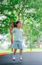 Asian child girl is jumping on trampoline on playground background. Happy laughing kid outdoors in the yard on summer vacation. Royalty Free Stock Photo