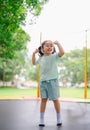 Asian child girl is jumping on trampoline on playground background. Happy laughing kid outdoors in the yard on summer vacation. Royalty Free Stock Photo