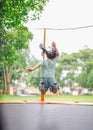 Asian child girl is jumping on trampoline on playground background. Happy laughing kid outdoors in the yard on summer vacation. Royalty Free Stock Photo