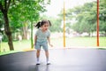 Asian child girl is jumping on trampoline on playground background. Happy laughing kid outdoors in the yard on summer vacation. Royalty Free Stock Photo