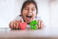 Asian child girl playing with plasticine clay house and heart with fun. Happy family and warm house concept