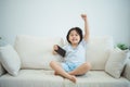 Asian child girl raise your hand cheerful success looking using and touch mobile phone screen on couch sofa. Baby smiling funny