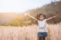 Asian child girl running and playing with toy wooden airplane in the barley field at sunset time with fun Royalty Free Stock Photo