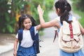 Asian child girl with school bag and her elder sister making hi five