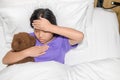 Asian child girl sickness lying on bed and put hand on forehead to check temperature